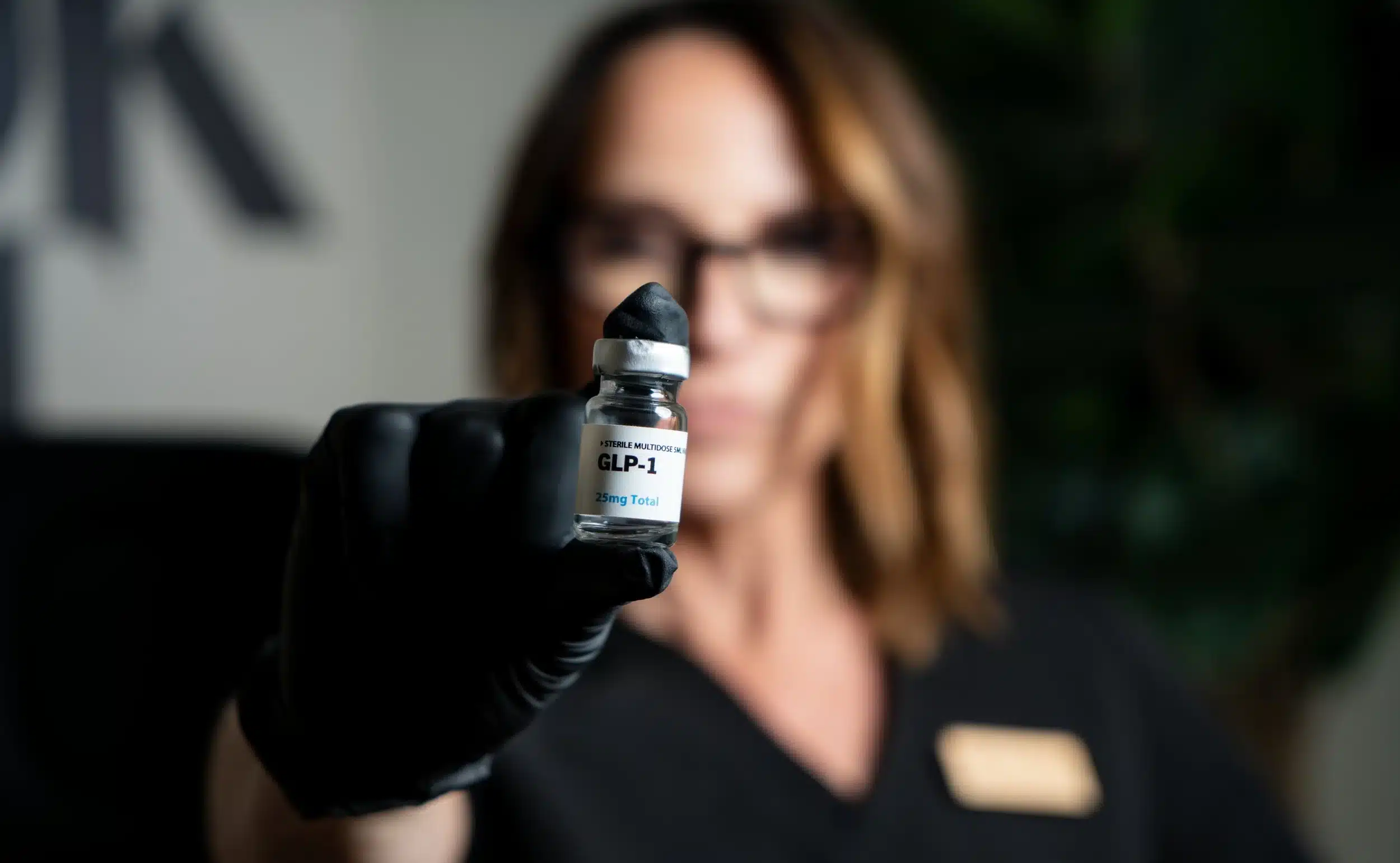 Person holding a vial labeled GLP-1, related to weight loss medication.